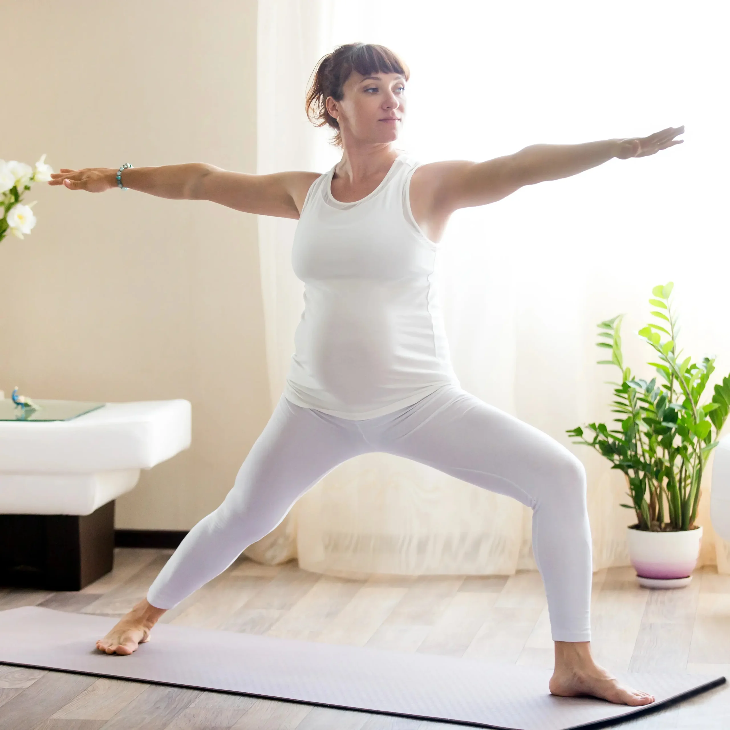 pregnant-woman-doing-warrior-two-yoga-pose-home (1) یوگا پس از بارداری - تصویر 1